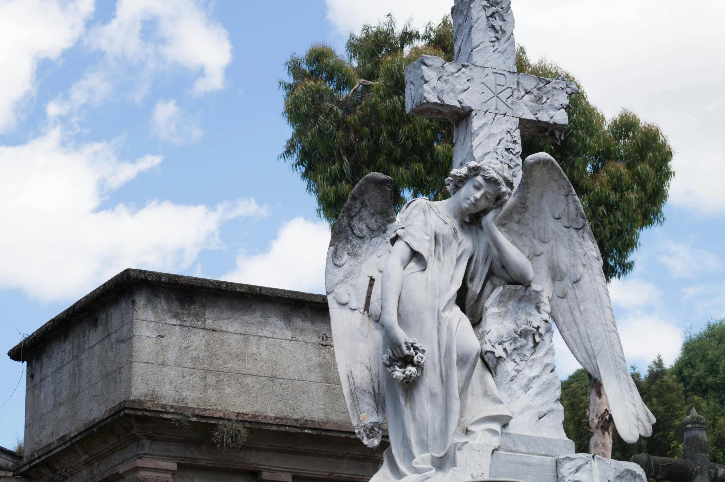 the statue is holding a cross on a stone slab