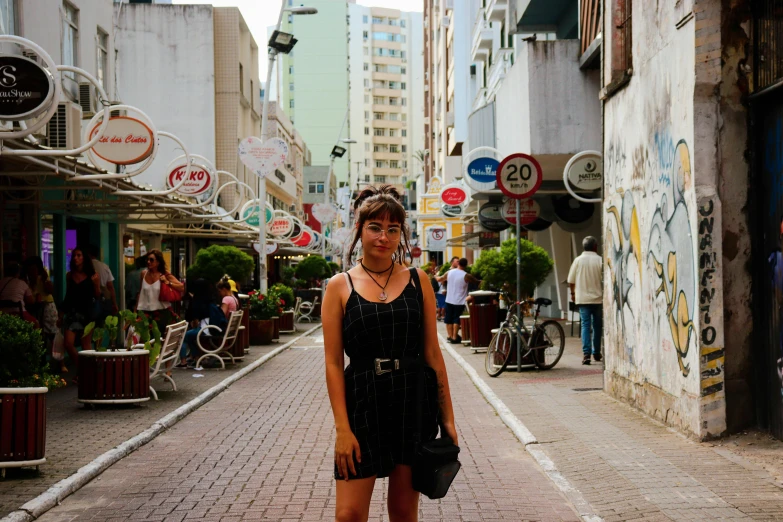 a woman stands in the middle of an alley with graffiti on the walls