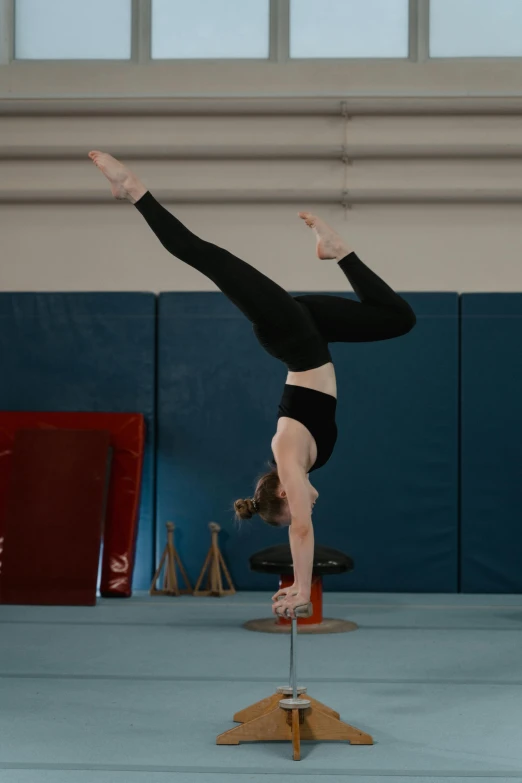 a young woman that is doing a back hand stand