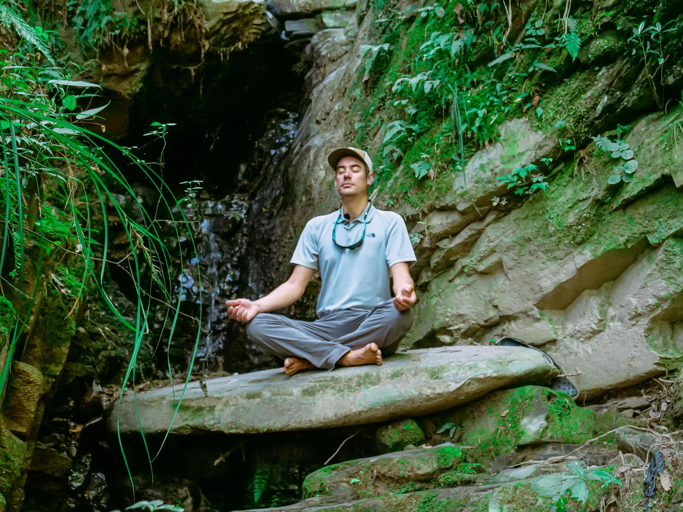 a man in gray shirt doing yoga on rock