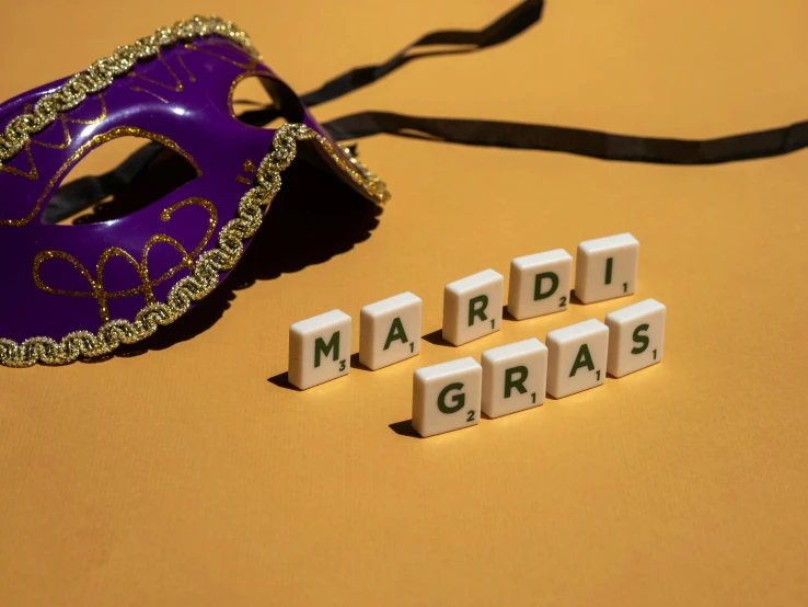the word mardi gras spelled in blocks by a mask