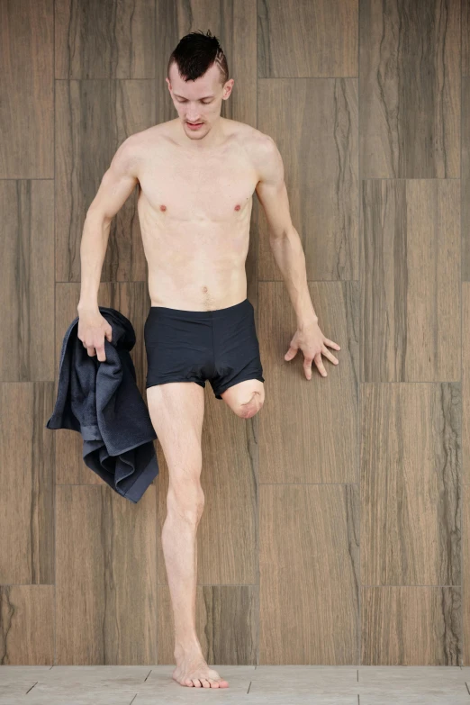 man standing in front of wooden wall with a towel around his waist