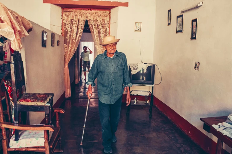 a man walking up a hall with a cane