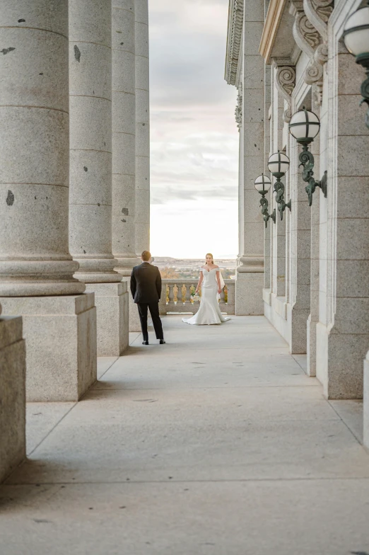 a bride and groom walking down an outdoor corridor
