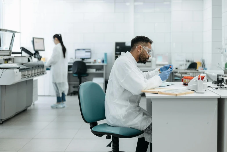 a man in white lab coat working on a desk