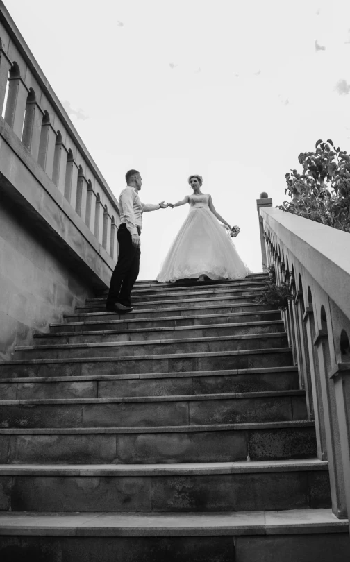 a man and a woman stand at the bottom of stairs
