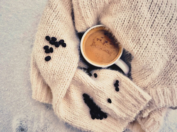 there is a cup of coffee on top of the white blanket