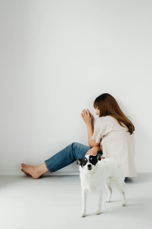 a little girl sits on the ground next to a dog