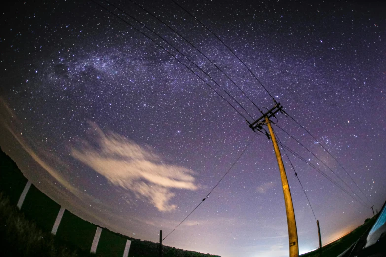 the night sky and stars above a power pole