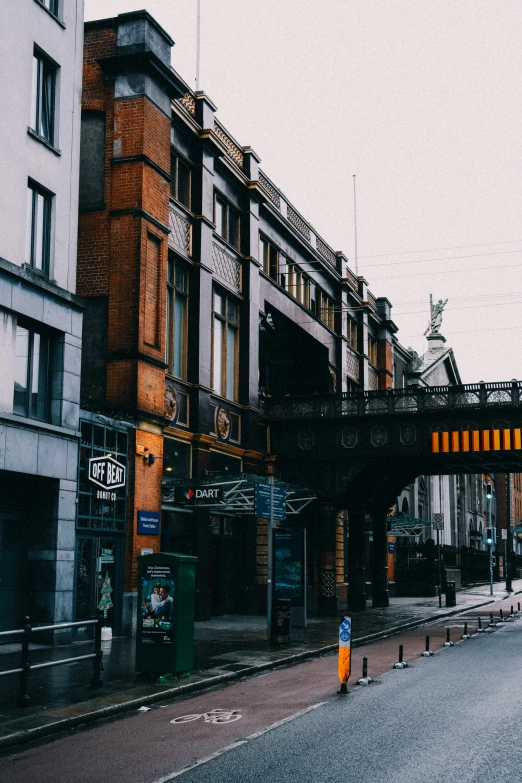 a lone pedestrian walks down a street below a bridge
