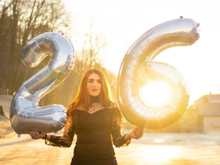 a woman is holding silver and white balloons