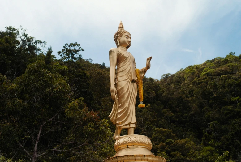 a large buddha statue holding a yellow cloth