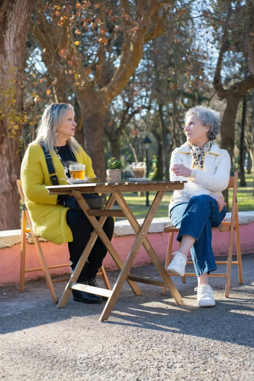 two women are sitting outside drinking drinks