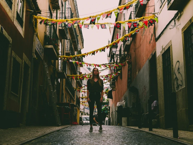 an alley way with flags and other decorations hanging above it