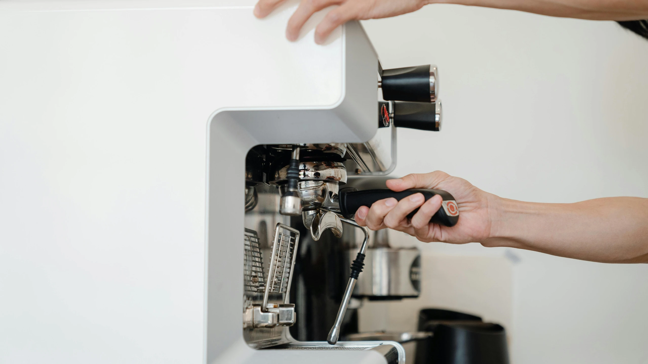 a man checking his coffee machine and fixing the espresso