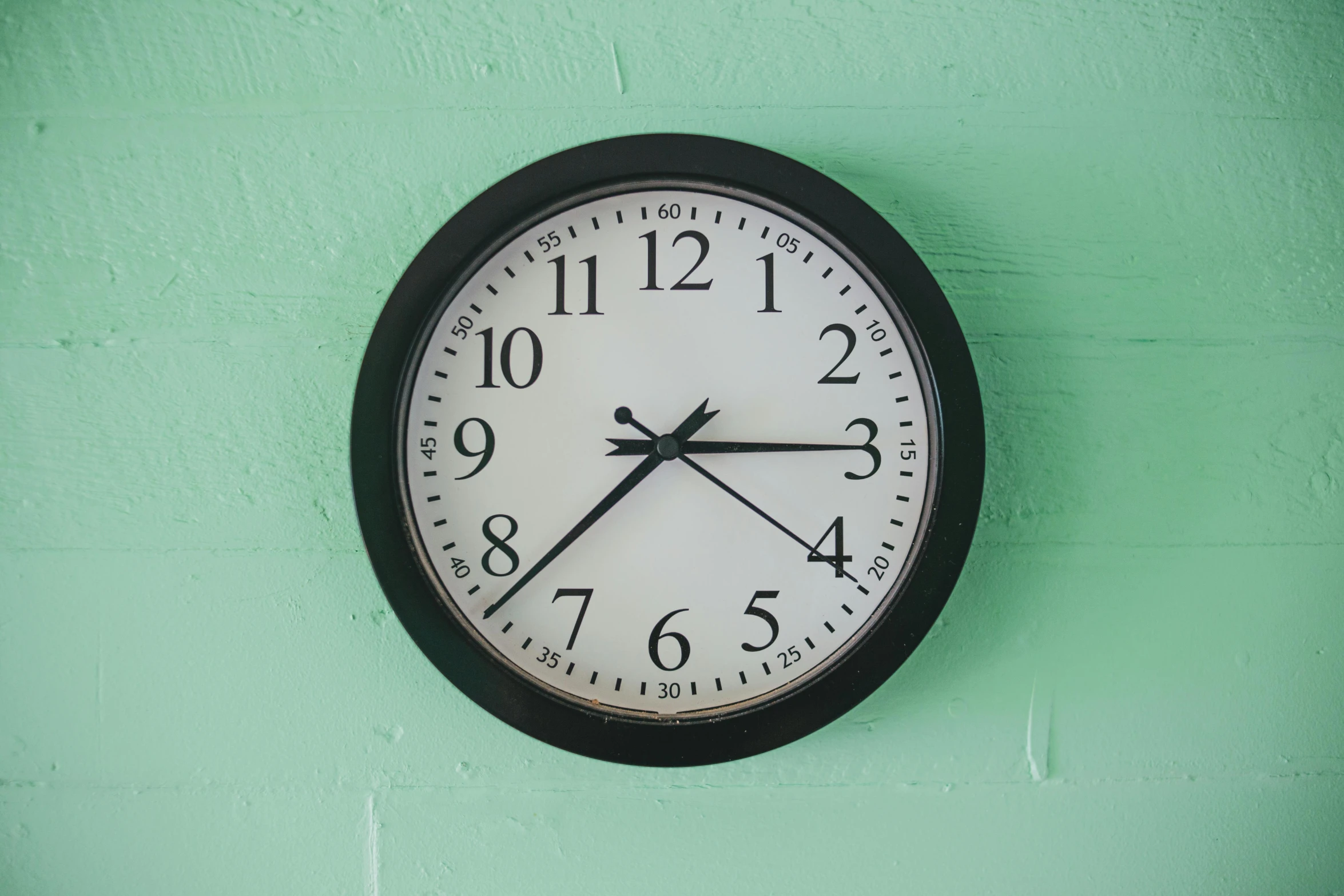 a clock on the wall is shown on a green surface