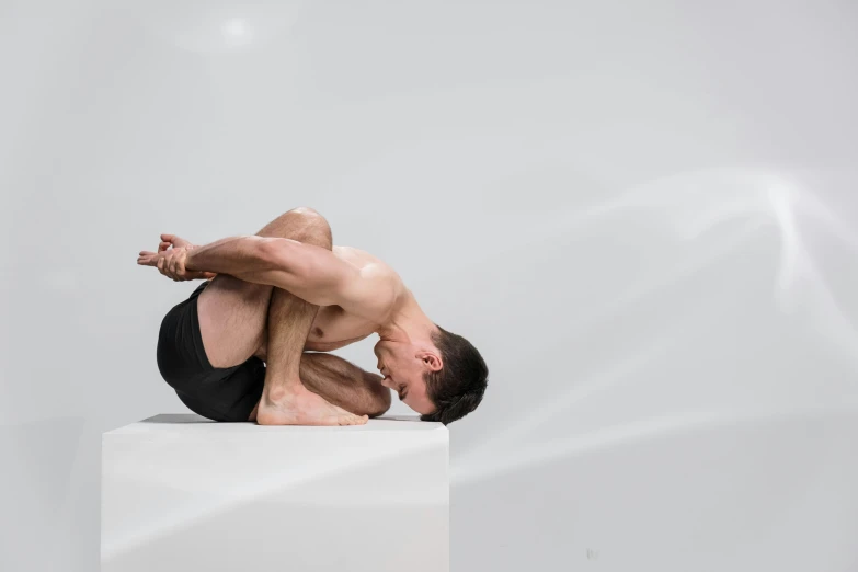 a man kneeling down on top of a white block