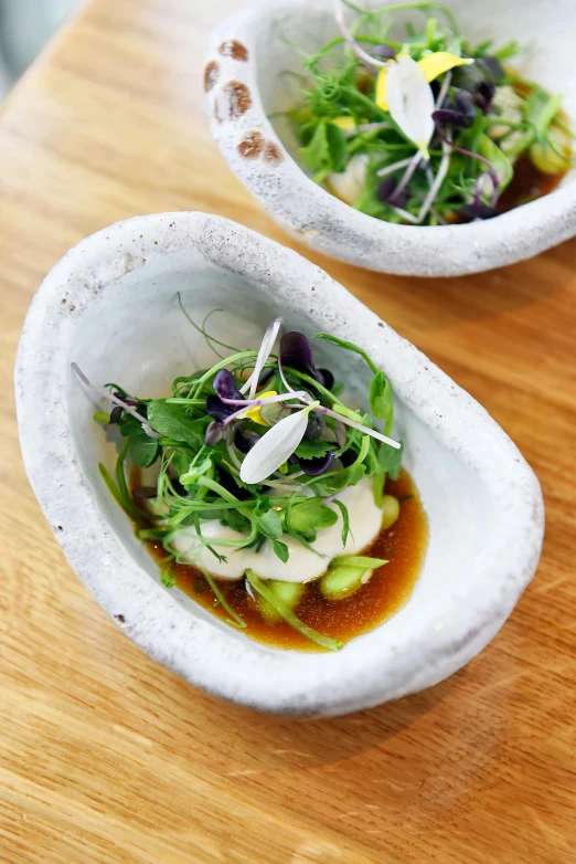 two bowls of salad sit on a table top