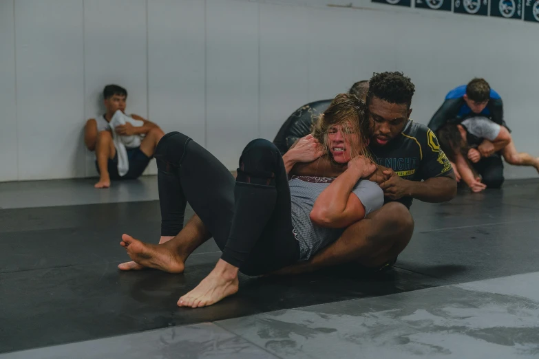 people wrestling on a black mat and one man lifting another