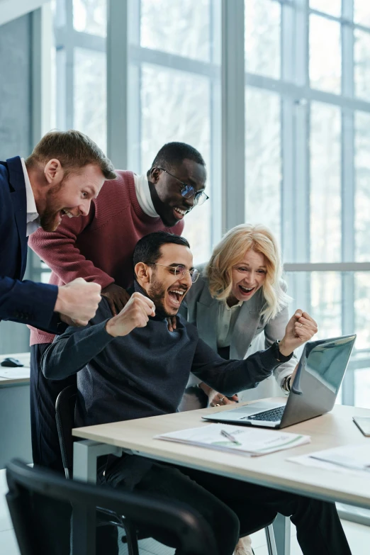 people celeting and sitting at a table using a laptop