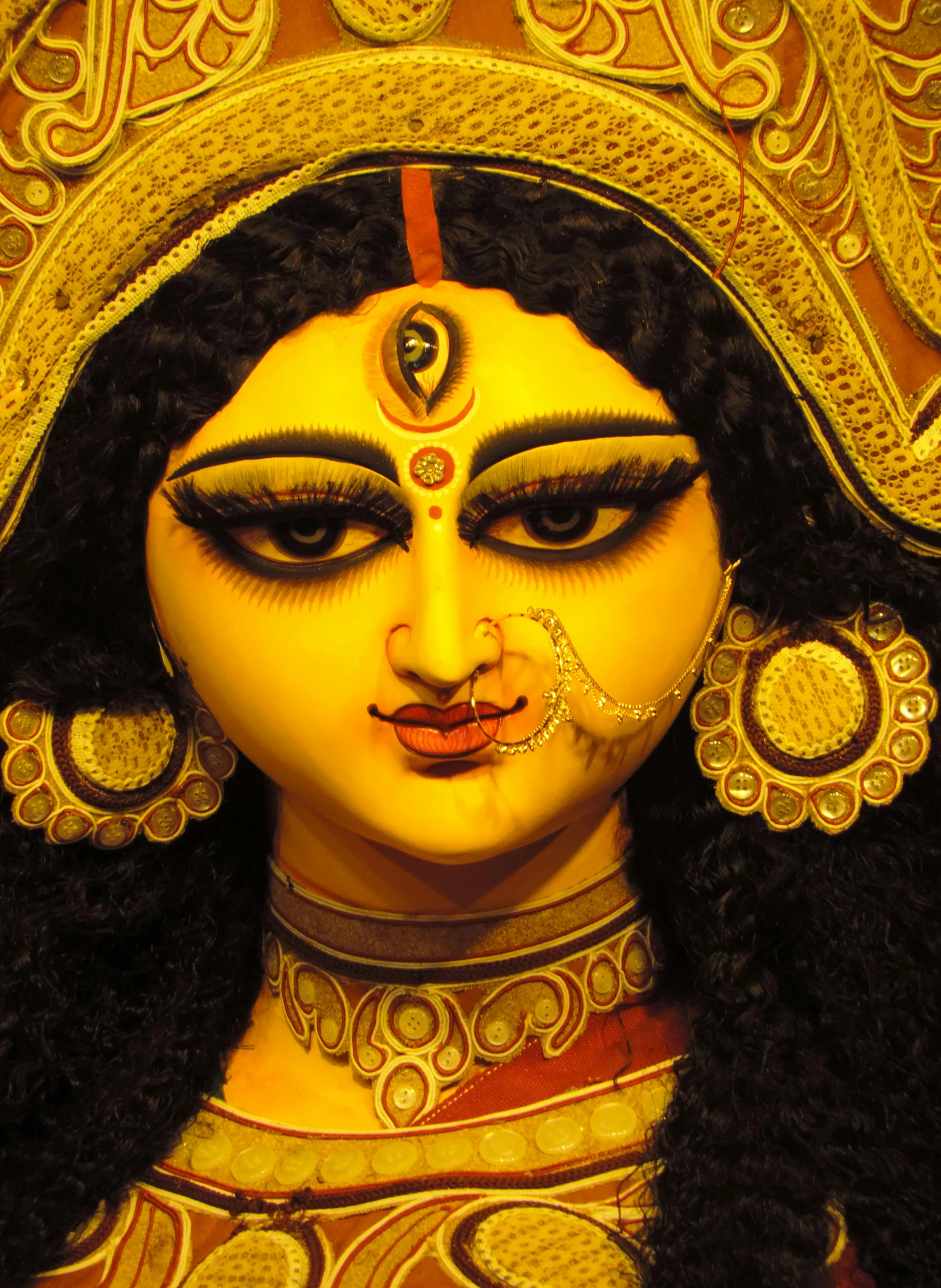 a statue wearing gold and ornate makeup
