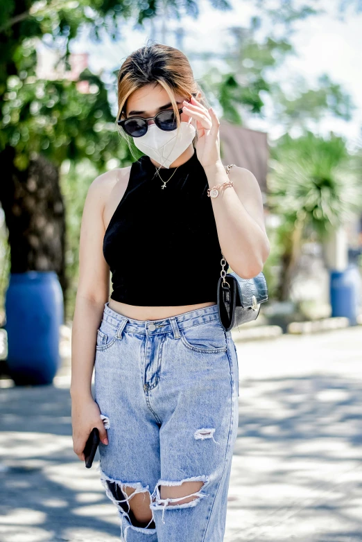 a woman with black sunglasses and a mask is posing on the street