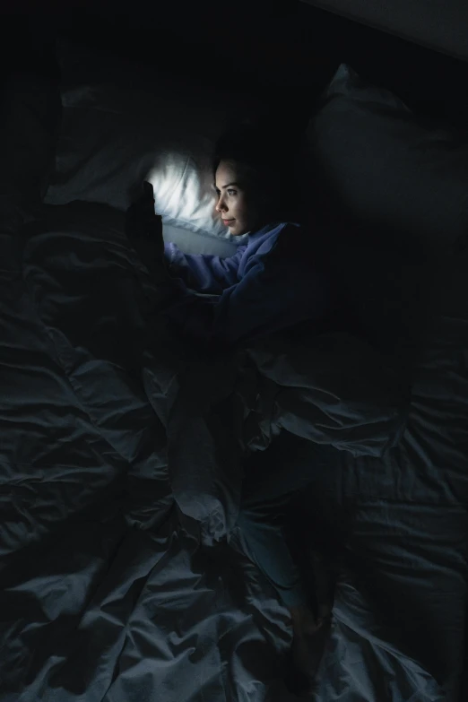 the woman is laying down in bed using a laptop computer