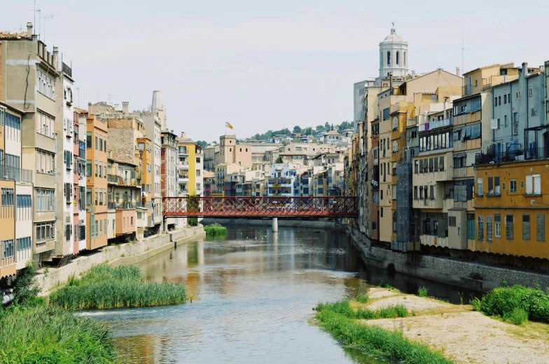 a river runs between two buildings with a bridge and sky in the background