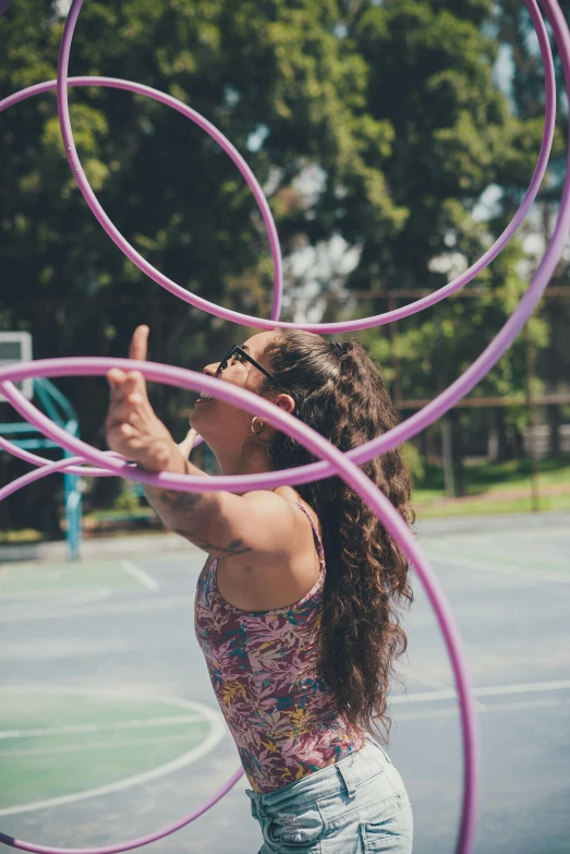 a woman holds a hoop with her fingers while on a basketball court