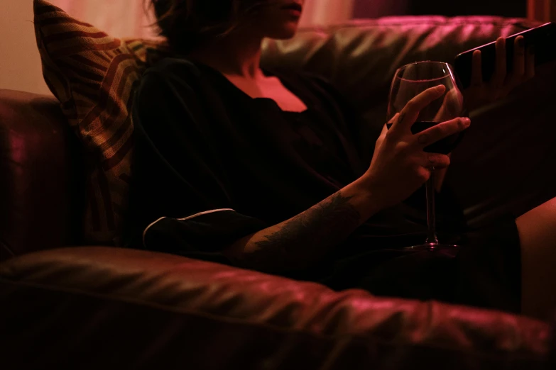 woman in black top holding up a glass of wine on couch