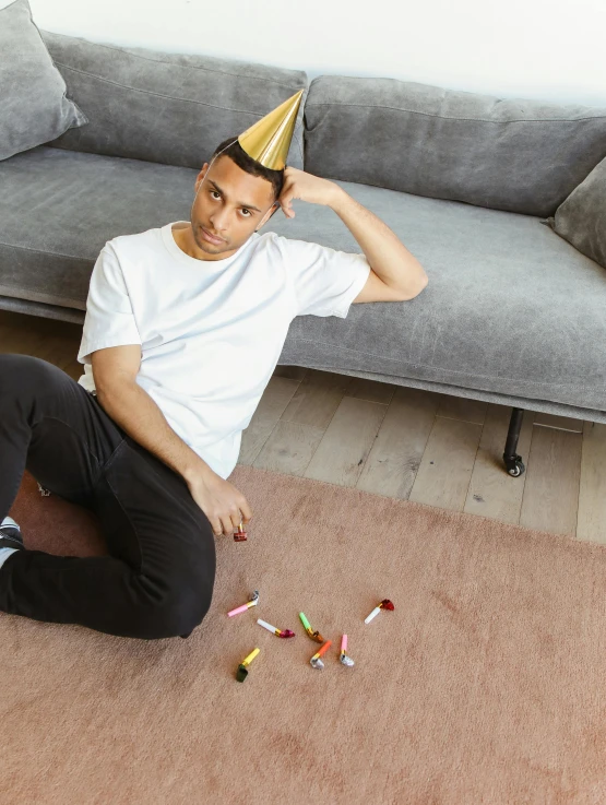 young man sitting on the floor with a party hat