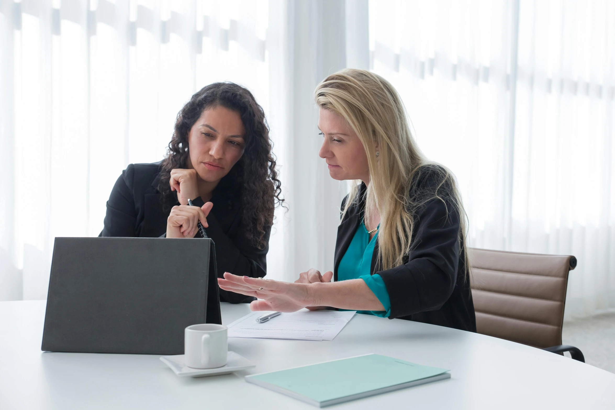 two women sitting at a table discussing paperwork