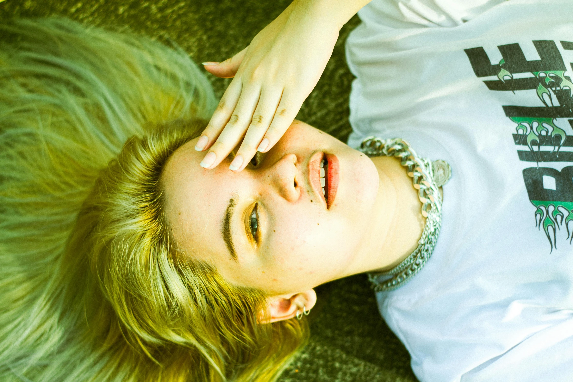 a girl laying on the ground next to her hand up and touching her hair