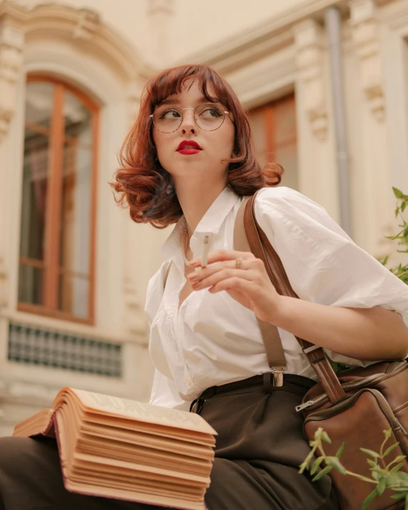 a woman with glasses, dress shirt and leather briefcase is sitting down