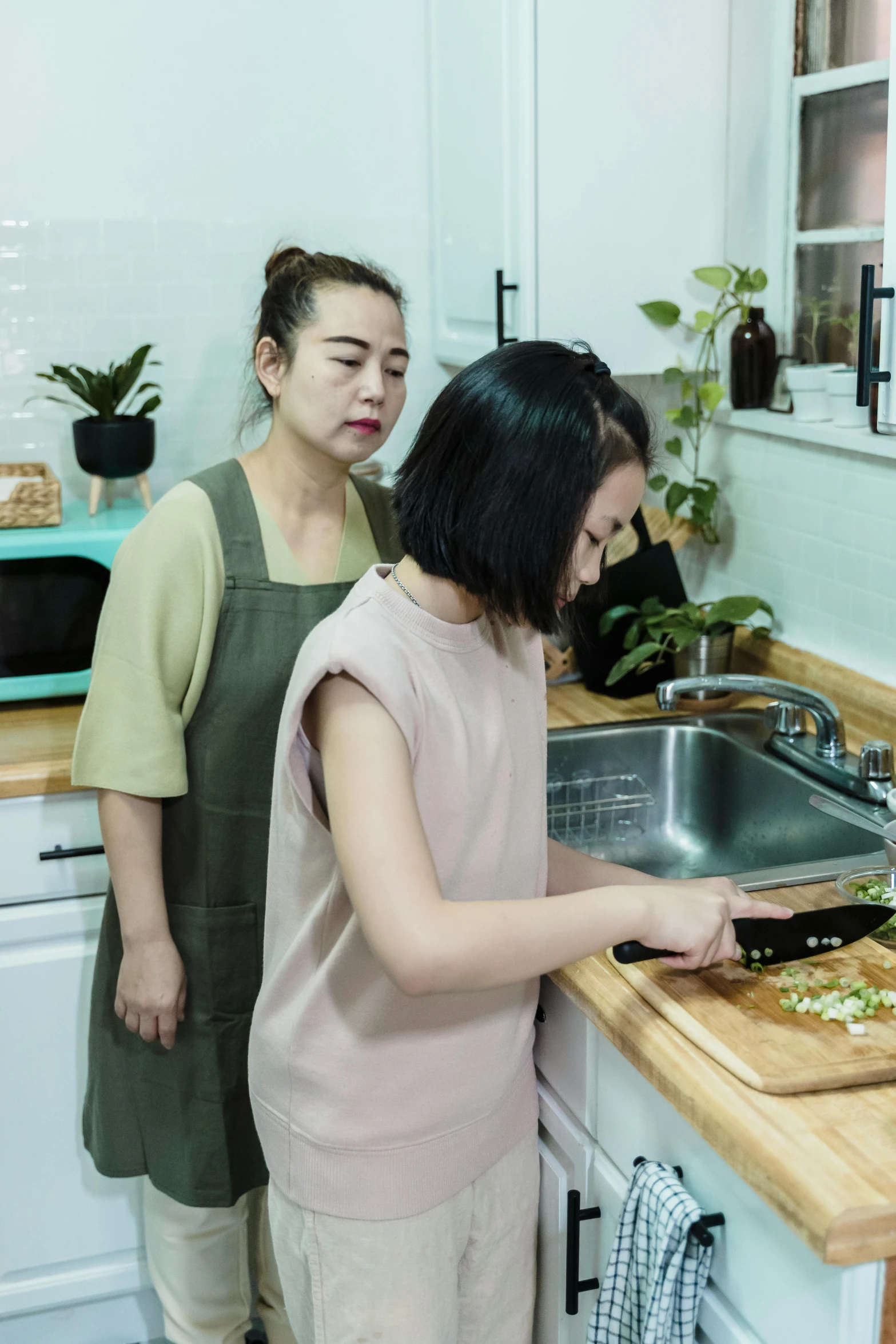 a couple of women standing in a kitchen cooking food
