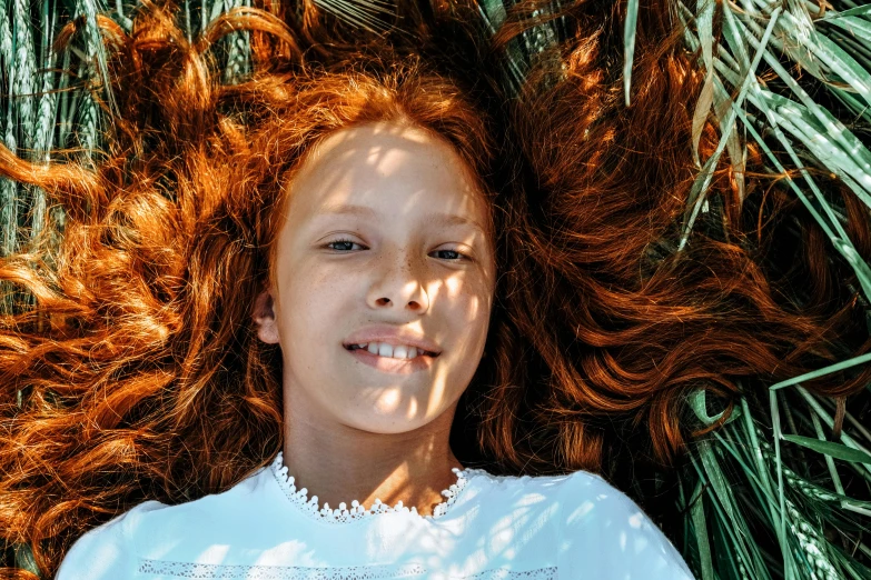 the young woman is laying down on grass