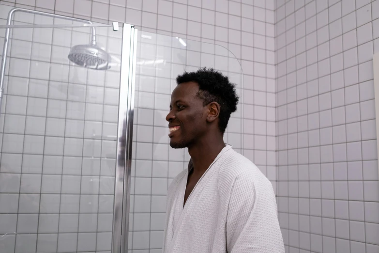 the black man is smiling next to the shower