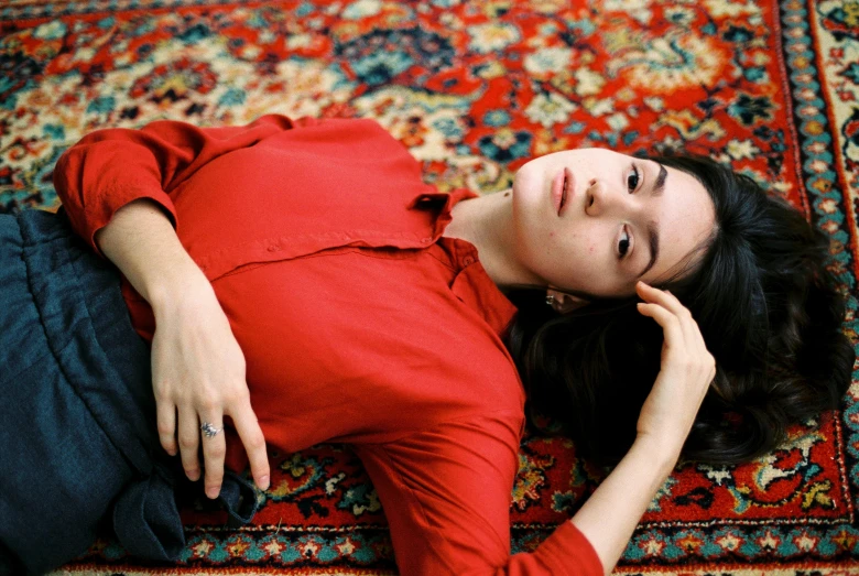 a woman with a red shirt laying on a rug