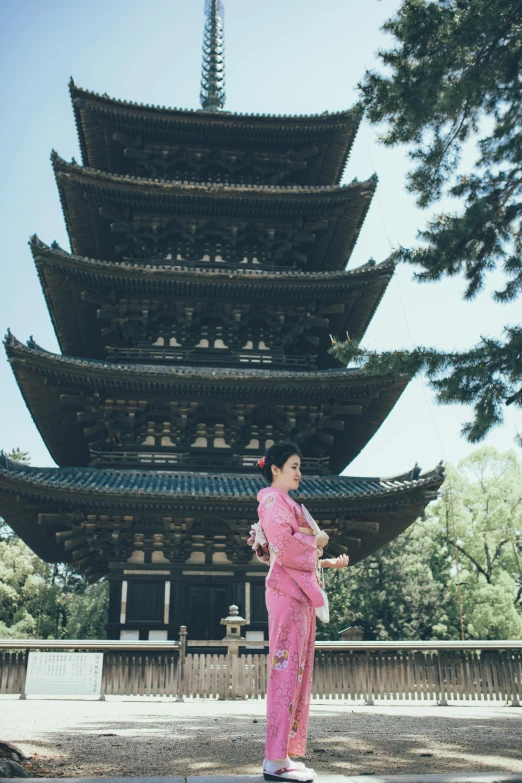 a woman in pink poses with a pagoda