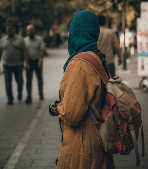 woman with backpack walking down the street in busy area