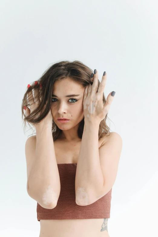 a beautiful young woman posing with her hands on her head