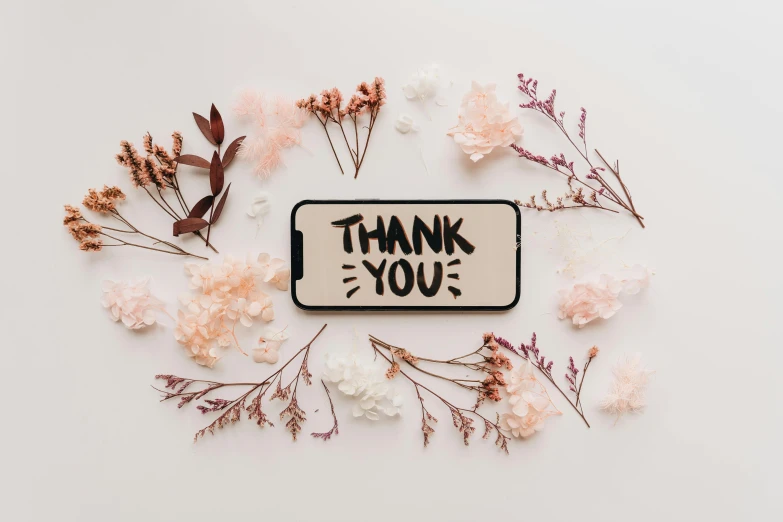 flowers and herbs surround the small thank you sign