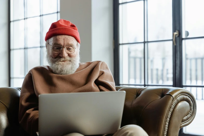 a man with a beard and wearing a red hat sits in a chair