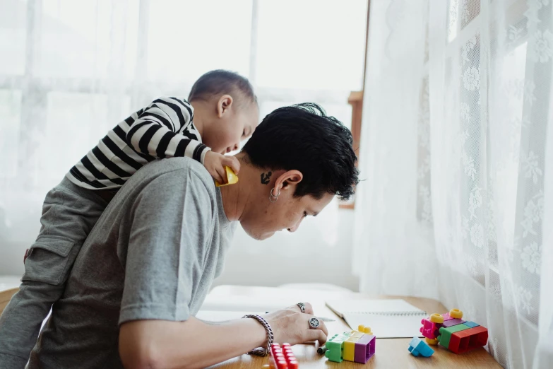 a woman holding onto her toddler playing with blocks on the floor