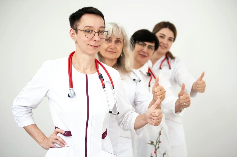 three medical staff giving thumbs up in front of a white background