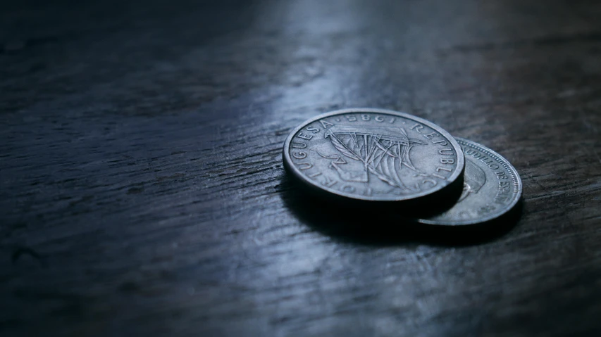 two one hundred rupee coins are stacked on a wood table