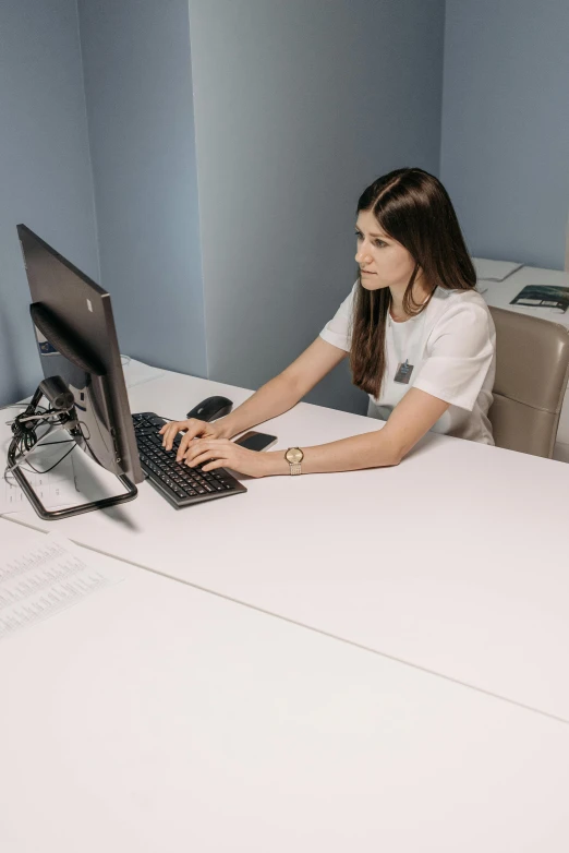 a woman in white shirt using a computer on a desk