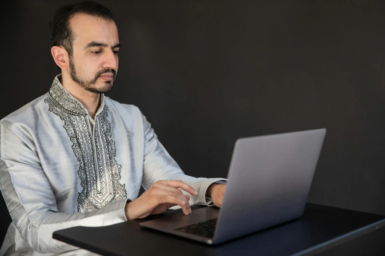 a man sitting at a table using his laptop