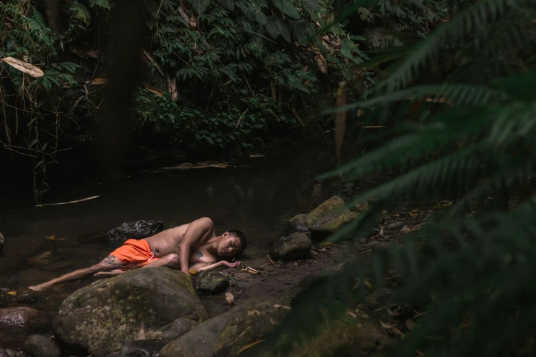 a person laying down on some rocks in the water