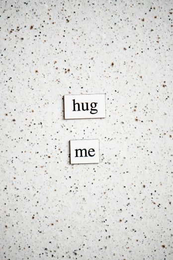 two rectangular tile signs with the words hug me above them